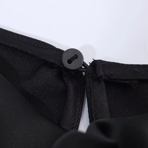 Detail of round button closure and hook design on black satin evening dress