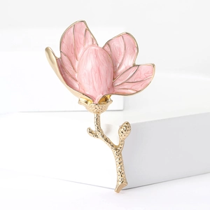 Elegant magnolia flower brooch with pink enamel petals and golden stem on white pedestal