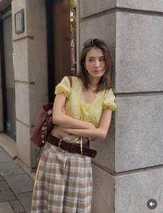Détail du haut court en dentelle jaune et jupe plissée à carreaux avec ceinture