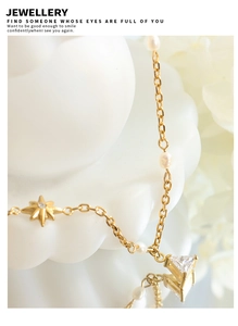 Close-up of star and triangle zircon pendant with freshwater pearl on gold chain