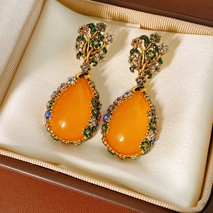 Macro view of vintage pear-shaped drop earrings with orange gems and colorful crystals