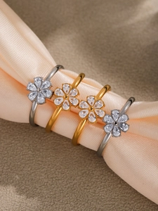 Macro shot of gold and silver flower rings with cubic zirconia on champagne silk