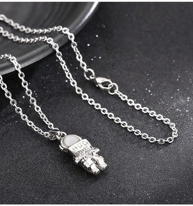 Detail of silver astronaut pendant featuring HUG engraving on a stainless steel chain