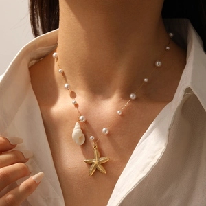Gros plan du collier marin doré avec perles, étoile de mer et coquillage sur modèle