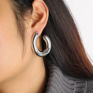 Close-up of polished silver C-shaped hoop earring worn by a model in a minimalist style
