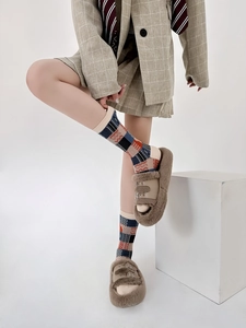 Close-up of vintage plaid socks in beige, blue and red worn with plush sandals