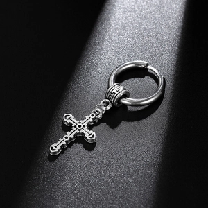 Macro detail of vintage silver steel cross earring with intricate gothic engravings