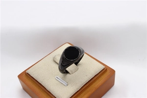 Detailed view of a polished black signet ring with a flat round face on a display stand