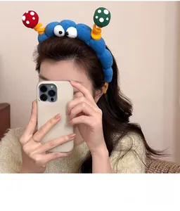 Close-up of blue plush headband with big eyes and spring mushrooms for face washing