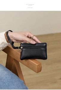 Detail of black lychee grain leather mini purse with gold zippers and wrist strap