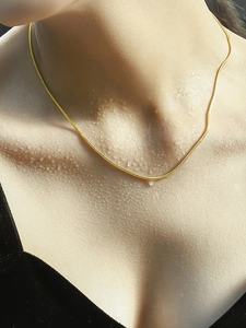 Close-up of waterproof 1mm gold snake chain necklace on skin with water droplets