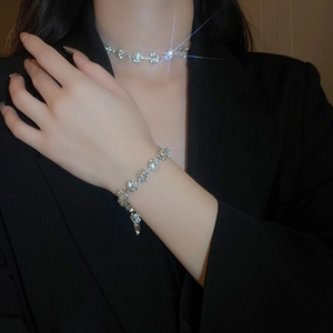 Gros plan d'un mannequin portant une parure collier et bracelet aux fleurs étincelantes