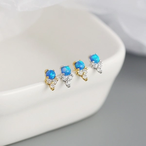Macro detail of blue opal stud earrings with tiny zircon accents on a white plate