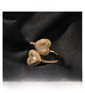 Close-up of golden twin heart ring with pavé crystals on a black silk background