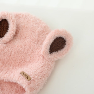 Detailed close-up of pink plush baby winter hat with cute brown knitted bear ears