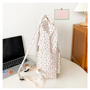 Side view of floral backpack on a minimalist desk with laptop and warm lighting