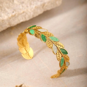 Macro detail of leaf-shaped enamel inlays on a gold-plated stainless steel open bangle