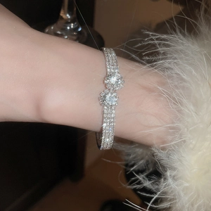 Close-up of sparkling crisscross bangle with pearls and diamonds on woman's wrist