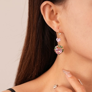 Detailed close-up of a pink heart crystal earring with colorful stones on female ear