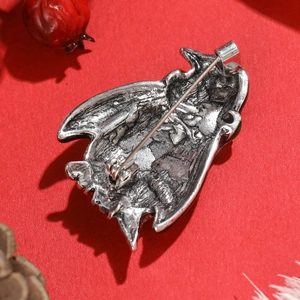 Macro view of vintage silver bat brooch back with sturdy pin on festive red background