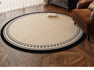 Detail of vintage French round rug with scroll patterns on a dark wood floor