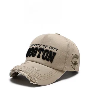 Detail of distressed brim and 3D Boston embroidery on a beige cotton baseball cap