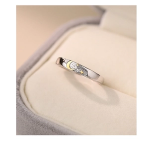 Close-up of silver ring with gold star and moon relief motifs in a jewelry box