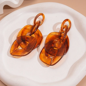 Amber acrylic chunky chain link earrings on a white tray with elegant lighting and shadows