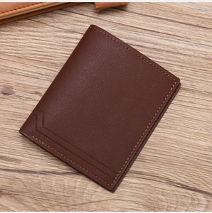 Detailed view of dark brown litchi grain leather bifold wallet on a wooden surface