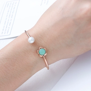 Rose gold open bangle featuring a white pearl and green crystal in a floral setting
