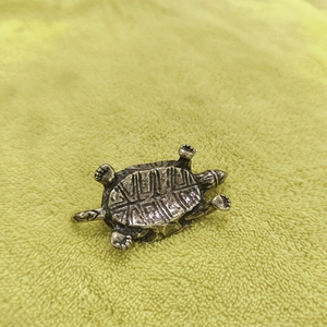 Handcrafted vintage brass tortoise figurine with detailed shell texture on fabric