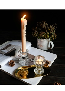 Close-up of ribbed glass candle holders on gold tray with warm ambient lighting