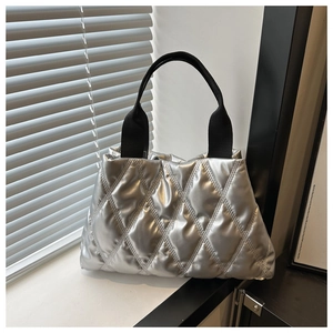 Detailed close-up of silver puffer tote bag with diamond quilted texture and black handle