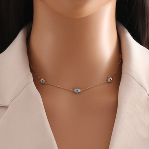 Golden necklace with multiple blue Hamsa Hand pendants worn by a model on a beige suit