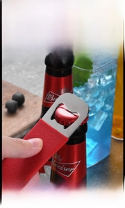 Macro shot of stainless steel bottle opener head lifting a cap with textured red handle