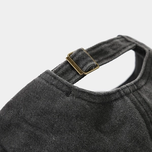 Detail of adjustable metal buckle and neat stitching on dark grey washed cotton baseball cap