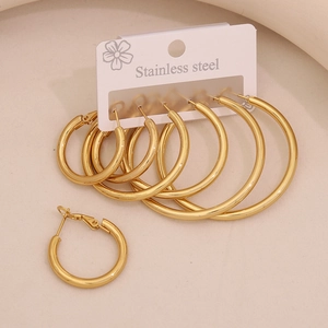 Three pairs of golden stainless steel hexagonal hoop earrings in multiple sizes on display