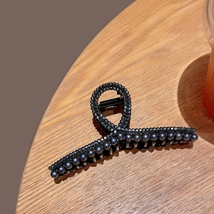 Elegant black twisted hair claw clip with dark beads and faceted gemstones on wood