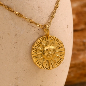 Vue macro du pendentif soleil doré avec symboles du zodiaque et détails de face céleste