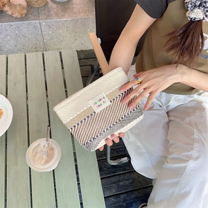 Close-up of a woven striped cosmetic bag with a label in a stylish lifestyle setting