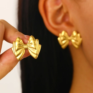 Detailed view of elegant gold bowknot earrings worn by a model for a minimalist chic look