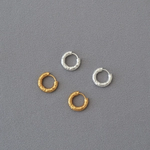 Macro detail of hammered gold and silver texture on minimalist circular hoop earrings