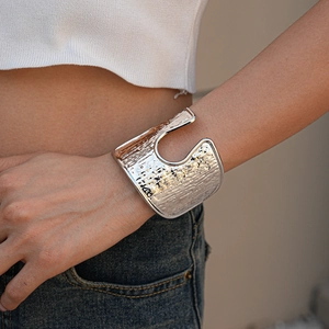 Macro shot of silver wide open cuff bracelet with textured hammered metal finish