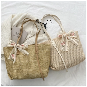 Close-up of straw woven tote bags featuring lace flower bows on white linen background