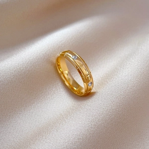 Detailed view of golden geometric ring with mesh engraving and three sparkling rhinestones