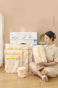 Detail of multi-size mesh laundry bags with bear print and yellow zipper on wood floor