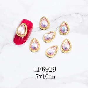 Detalle de diamantes de uñas de gota rosa 7x10mm con borde de metal dorado en mármol