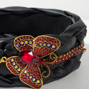 Nahaufnahme eines Leder Stirnbands mit einem Schmetterling aus roten Kristallen und Strass