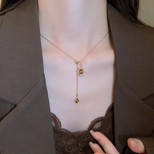 Gros plan d'un collier pendentif soleil doré avec œil de tigre sur un mannequin femme