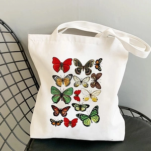 Detail of white canvas tote bag with butterfly print resting on a black chair